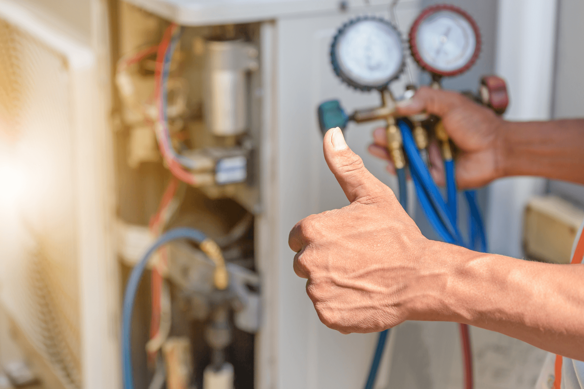 HVAC technician holding refrigerant gauges while servicing a cooling system in San Diego